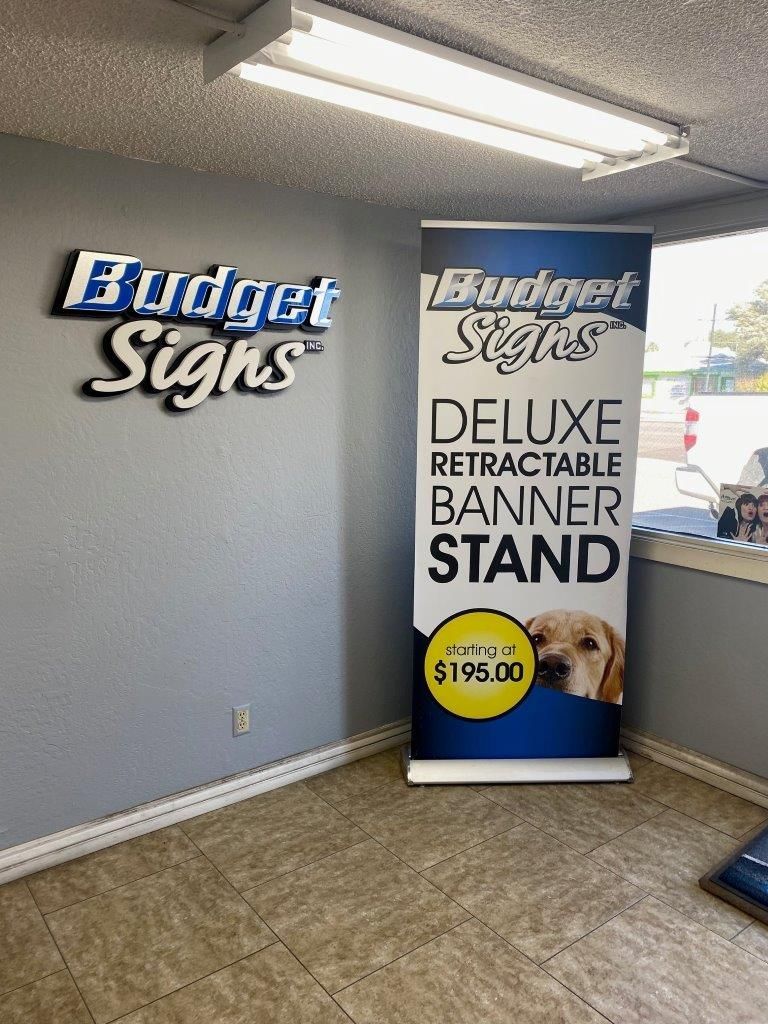 A deluxe retractable banner stand is sitting in a room next to a window.
