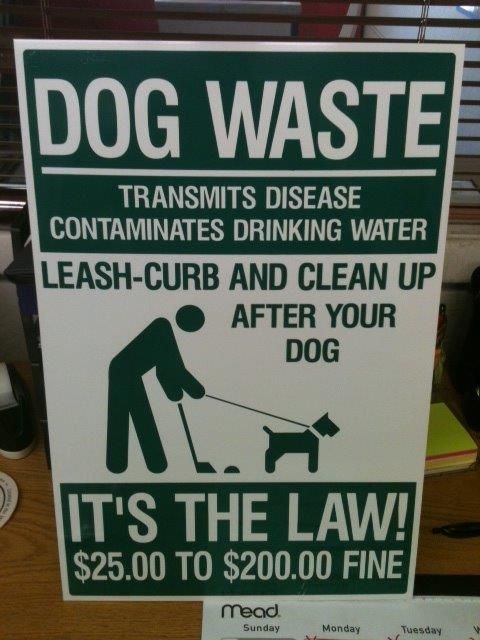A sign that says dog waste transmits disease contaminates drinking water leash-curb and clean up after your dog
