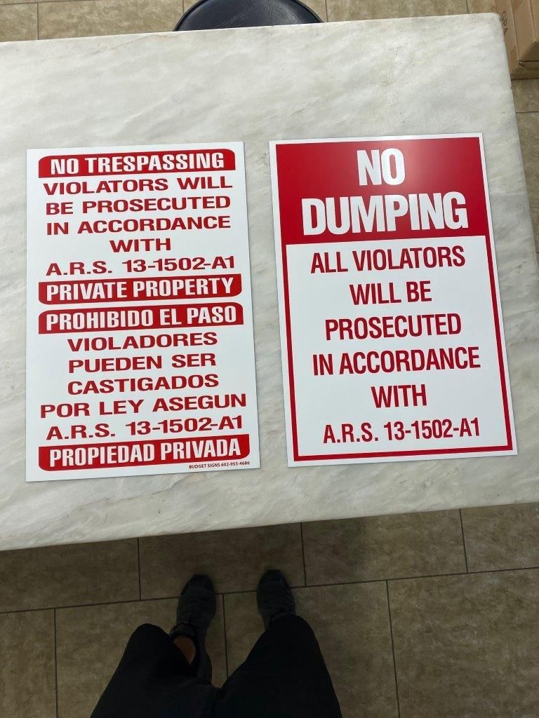 Two signs on a table that say no trespassing and no dumping