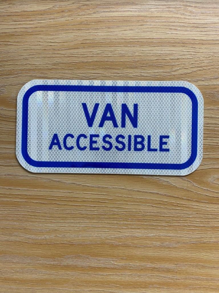 A van accessible sign is sitting on a wooden table.