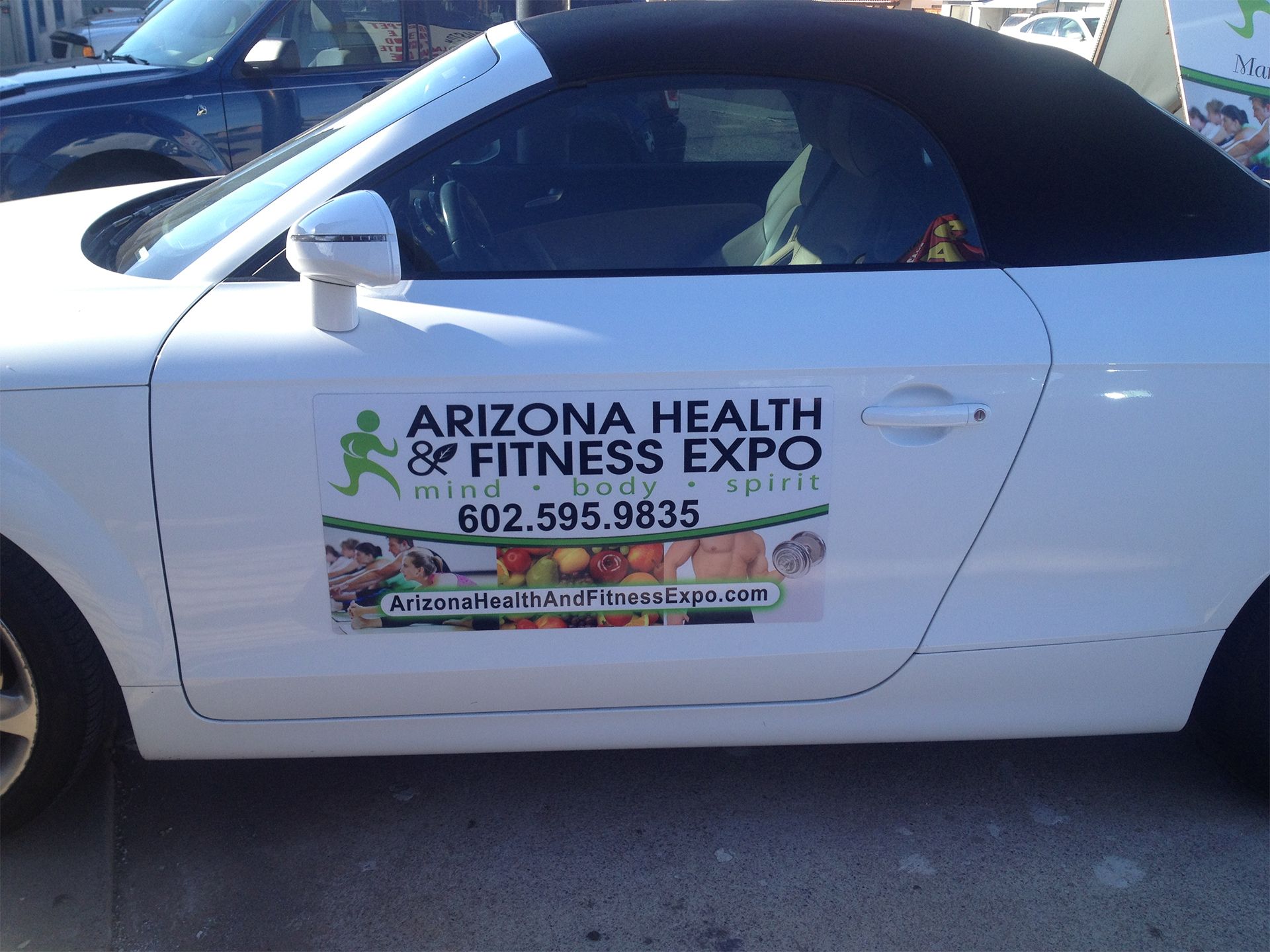 A white car with a sign on the side that says arizona health & fitness expo