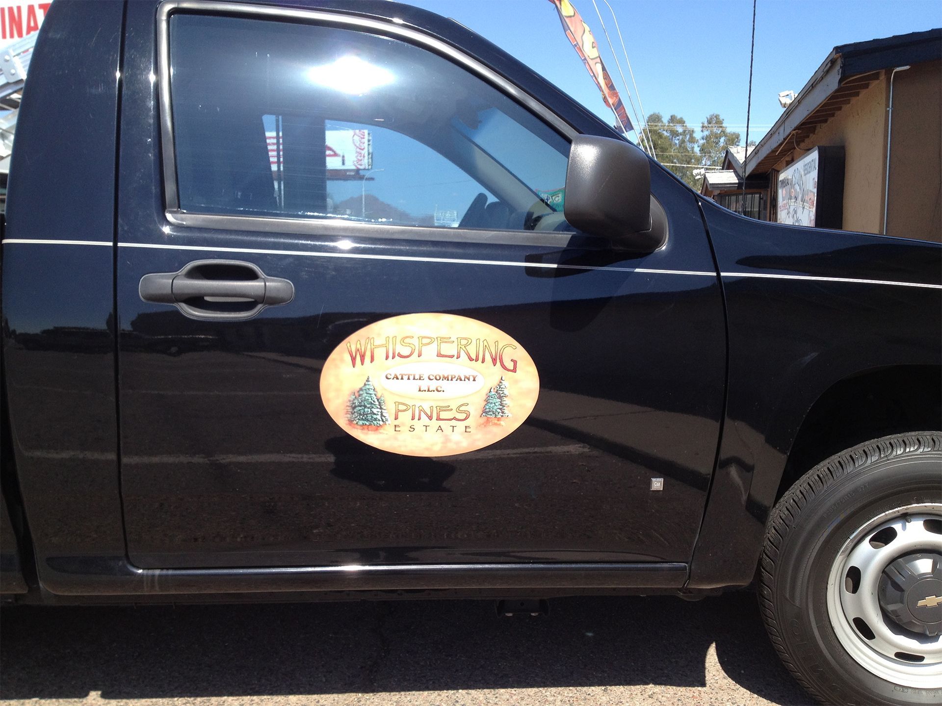 A black truck with a sticker on the side that says whistling pines