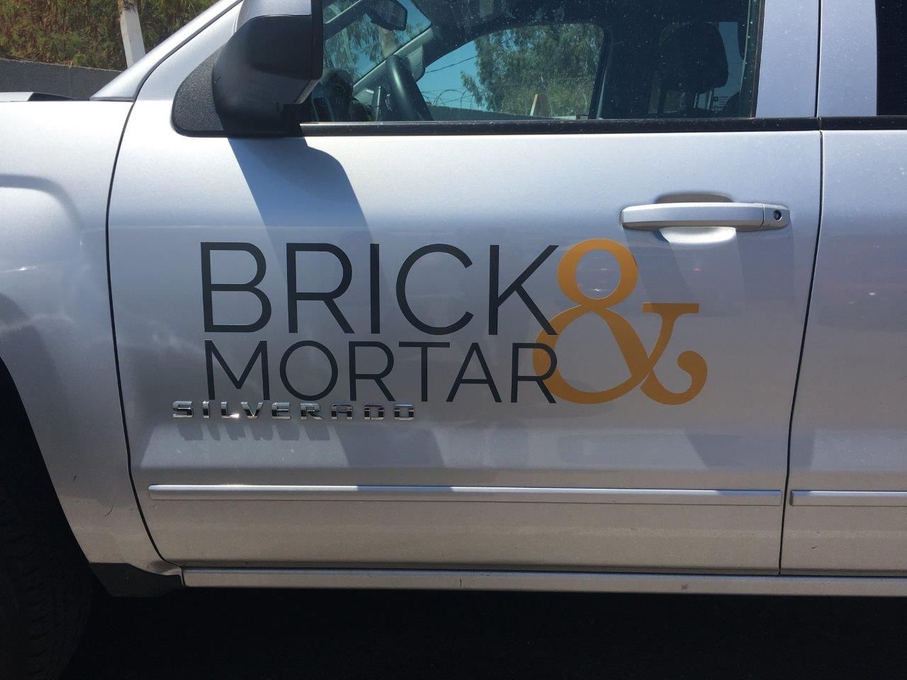 A silver truck with brick mortar written on the side