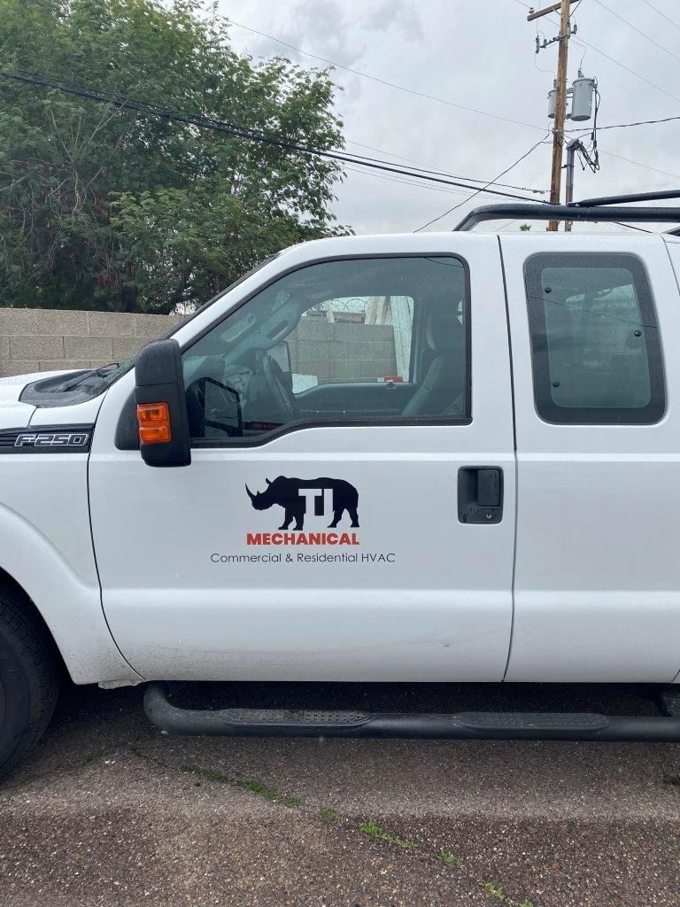 A white truck with a logo on the side is parked in a parking lot.
