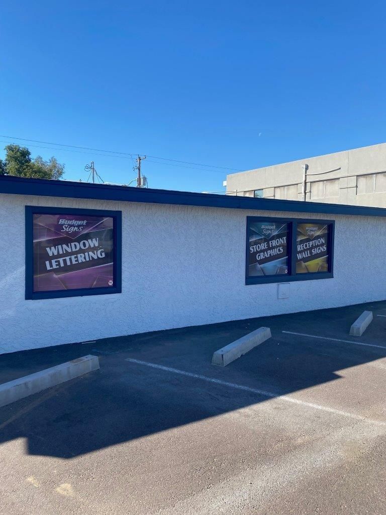 A white wall with two signs on it in a parking lot.