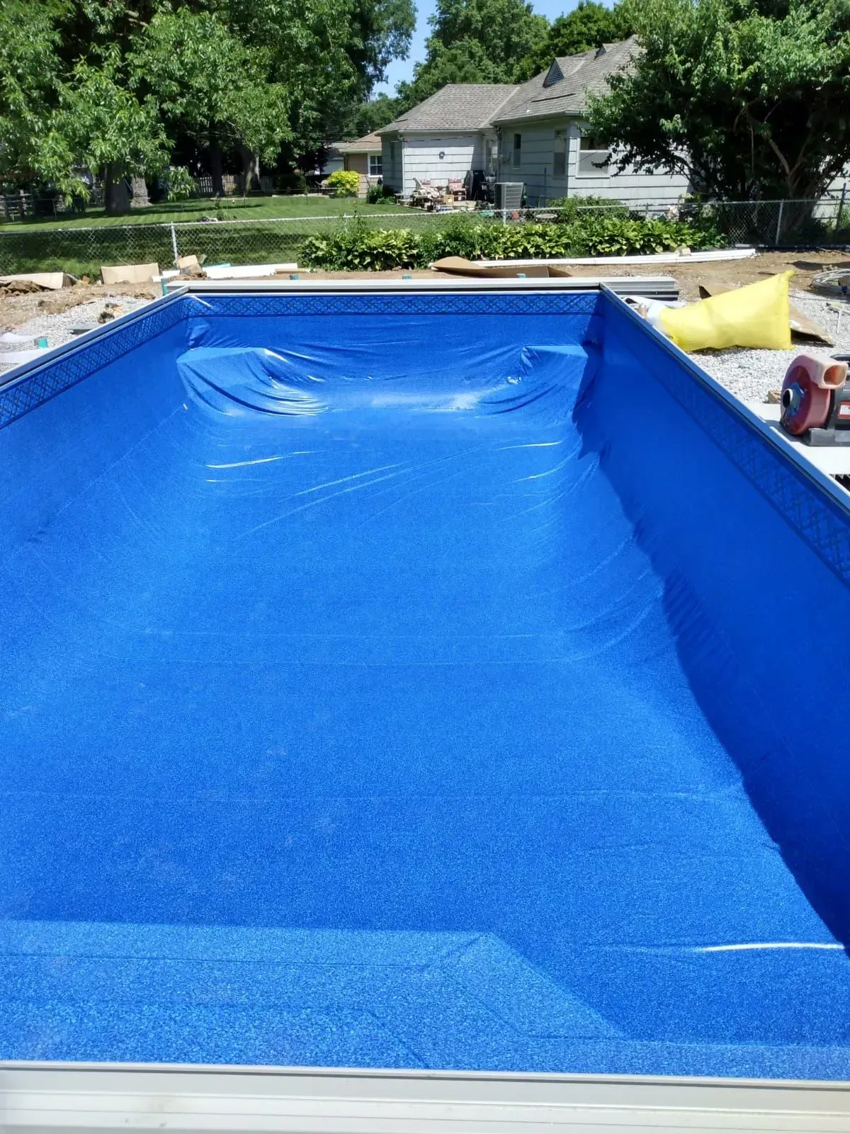 Blue vinyl liner installed in a rectangular in-ground swimming pool under construction.