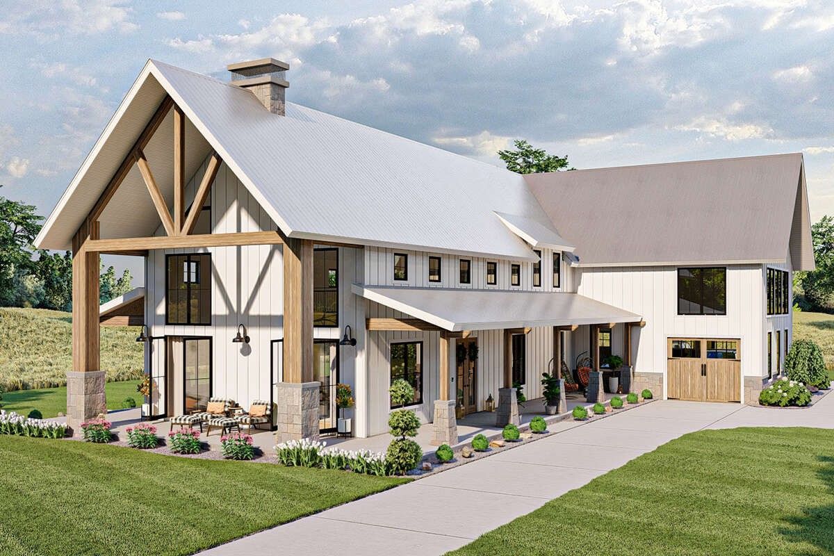 Modern white farmhouse with a steep roof, wood accents, and a front porch in a green rural setting