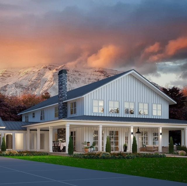 Modern white farmhouse with porch at sunset, backed by snowy mountains and pink clouds