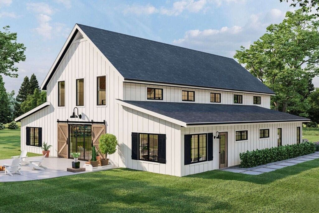 Modern white farmhouse with dark roof, large windows, and a covered porch in a green yard.