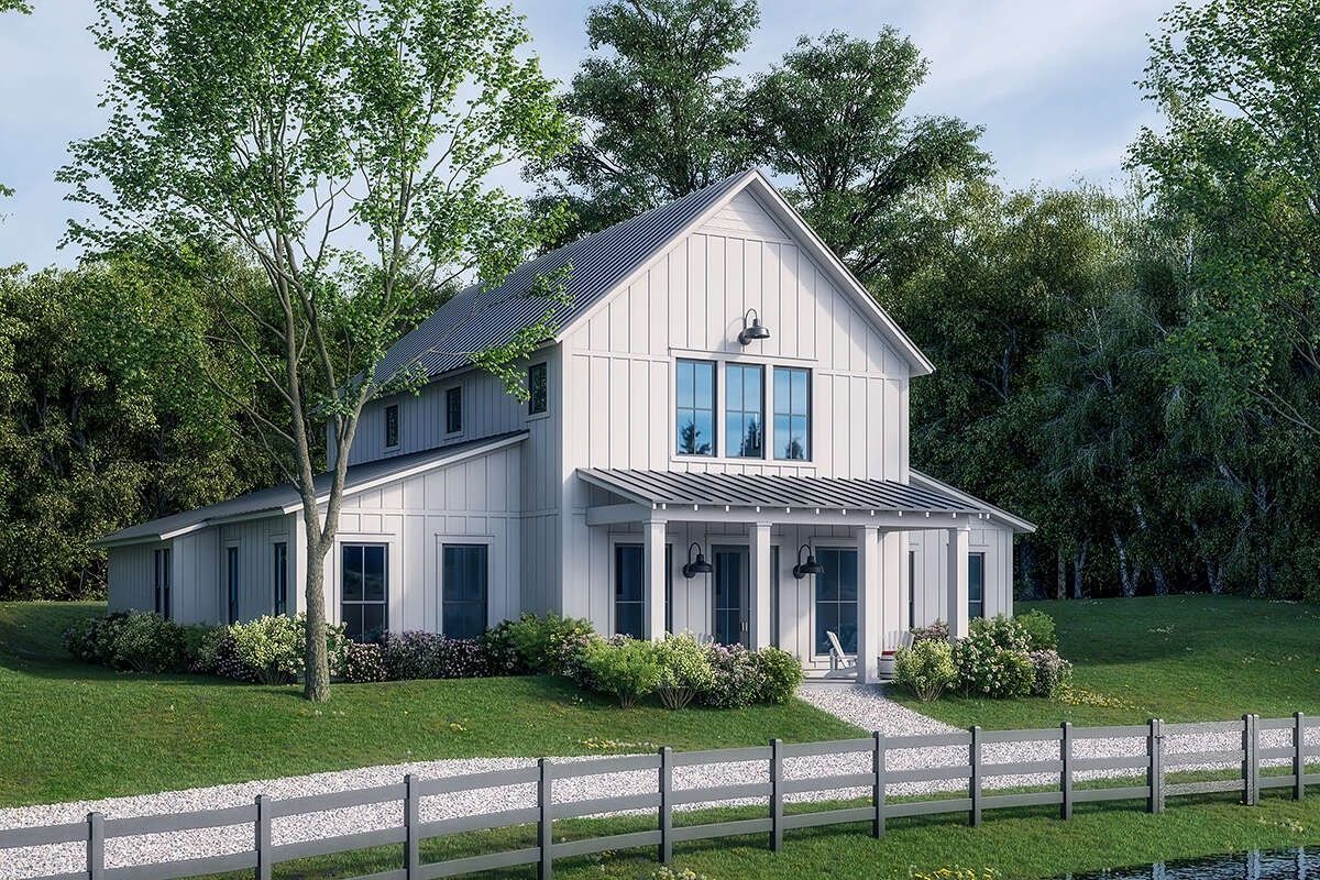 White farmhouse with blue accents beside a lawn and fence, surrounded by trees under a clear sky