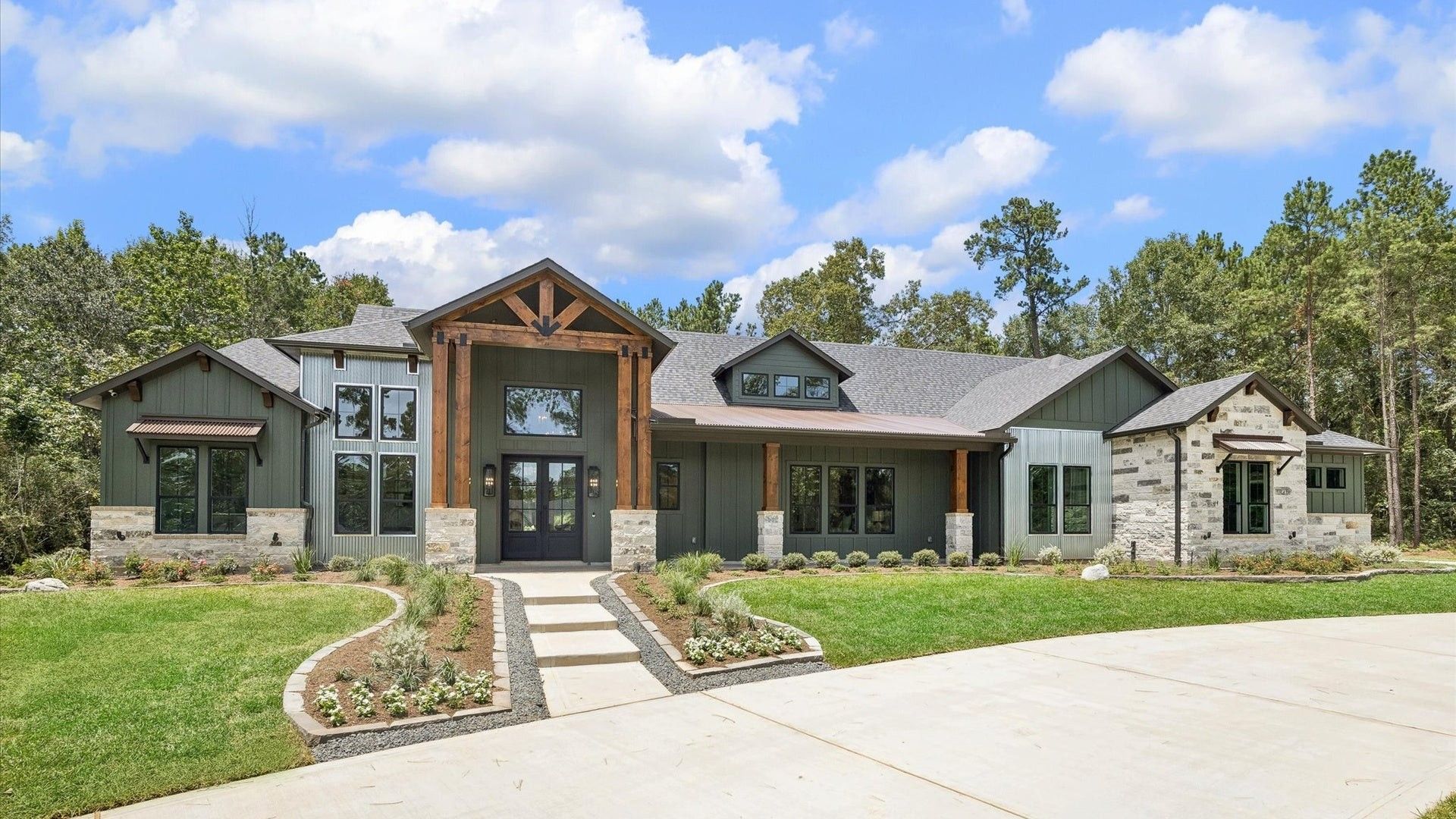 Modern suburban house with stone accents, front walkway, and landscaped yard under a blue sky
