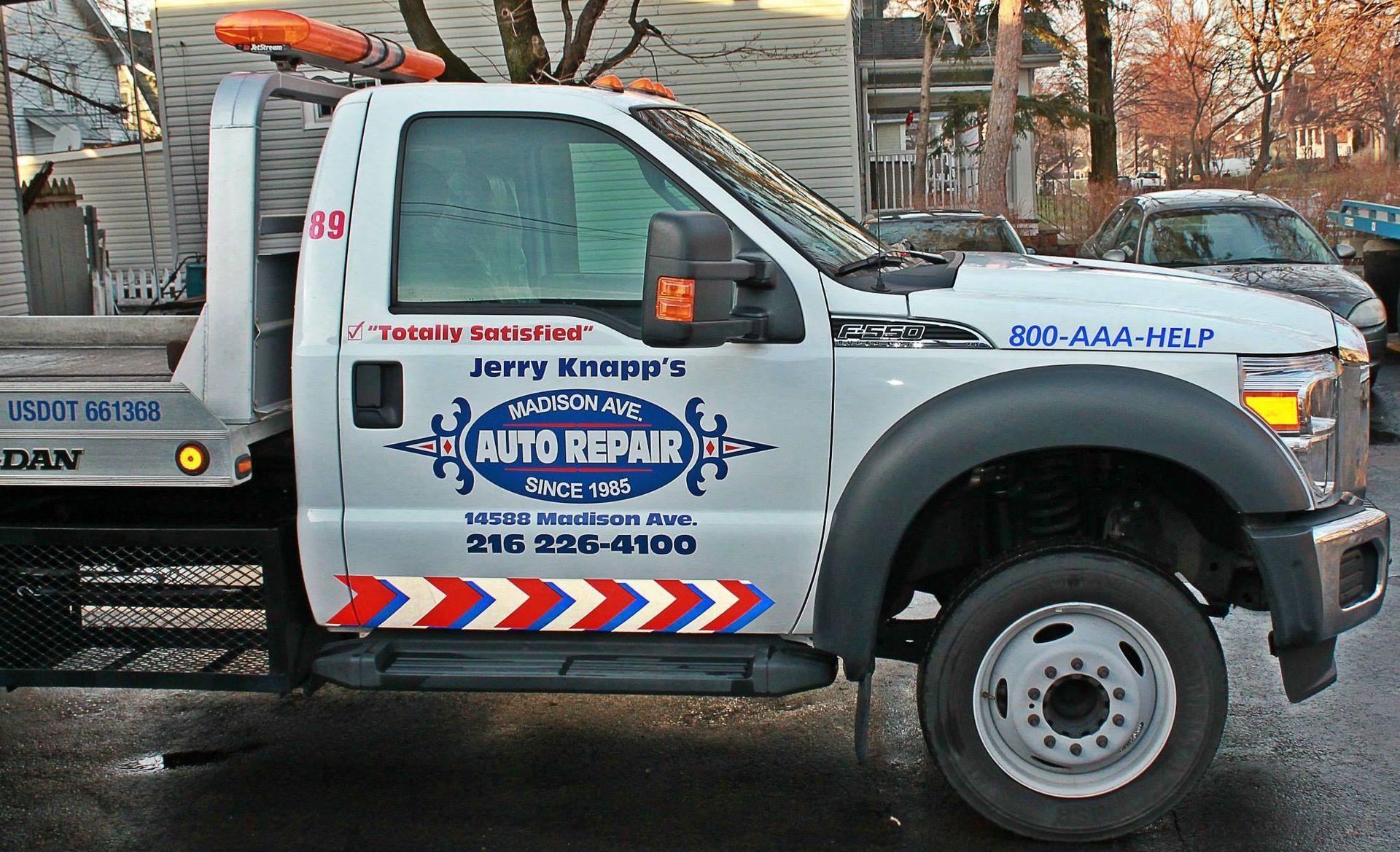 White tow truck with Jerry Knauer's Auto Repair logo and phone number, parked outdoors.