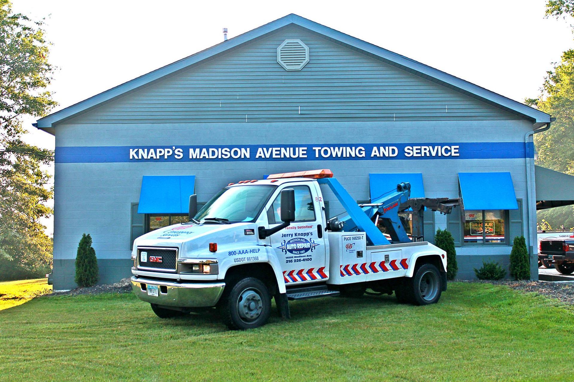 A tow truck parked in front of Knapp's Madison Avenue Towing and Service building, blue and white.