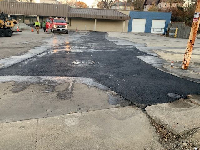 A red truck is parked in a parking lot next to a building.
