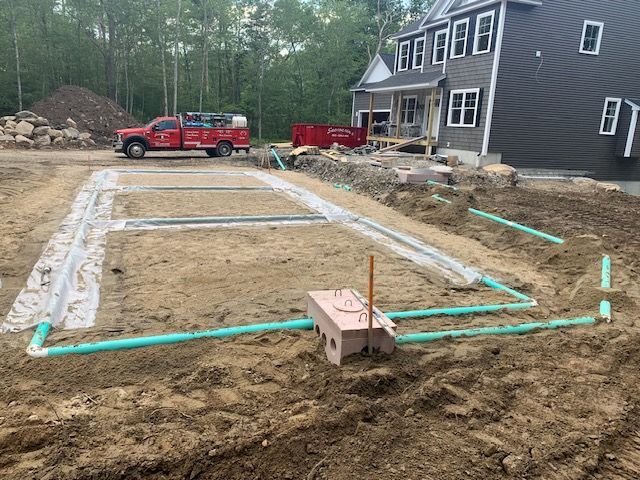 The green pipes laid out in the trenches for the water supply lines