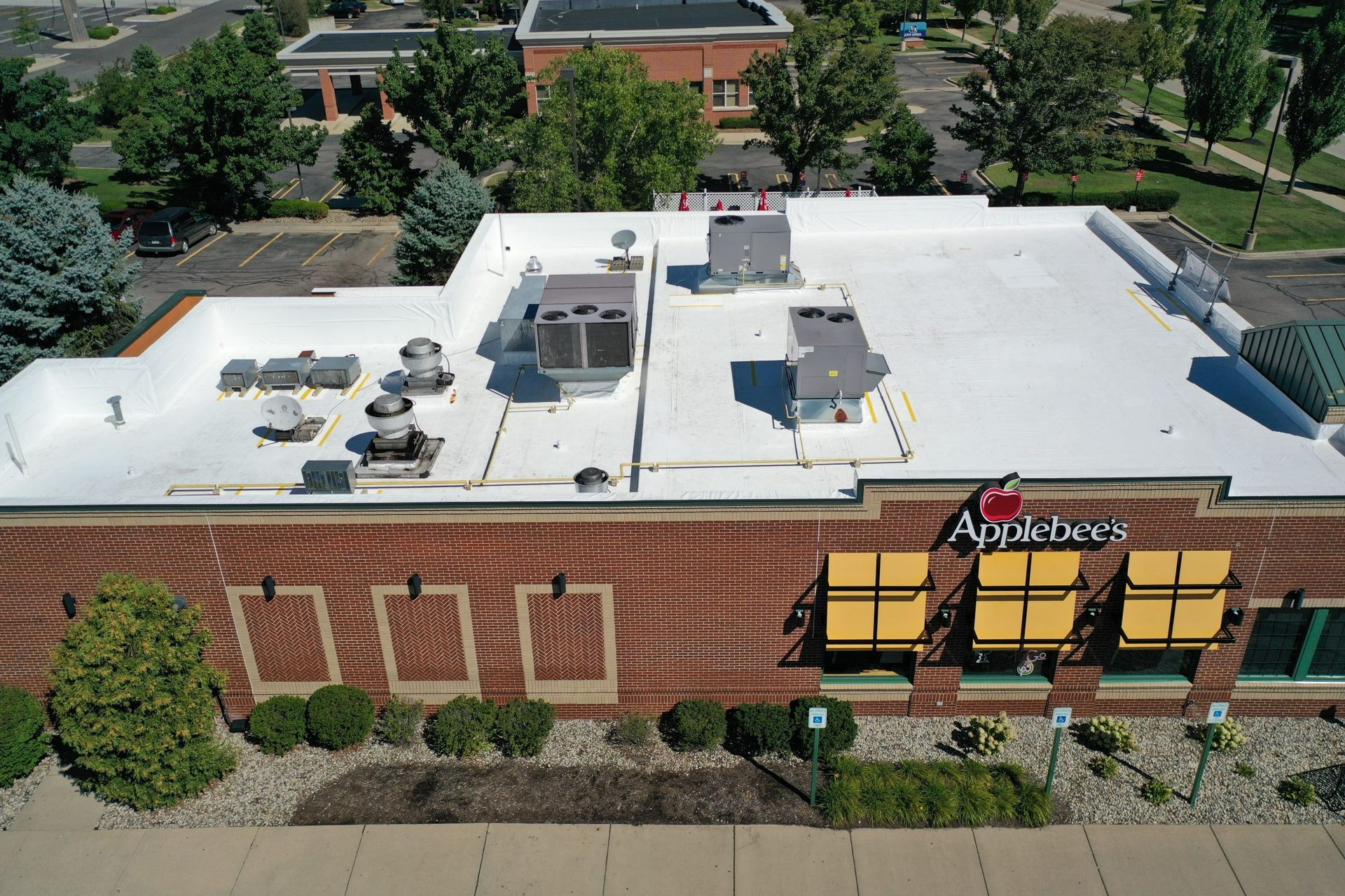 Aerial view of a brick Applebee’s restaurant with a white roof and outdoor patio tables.
