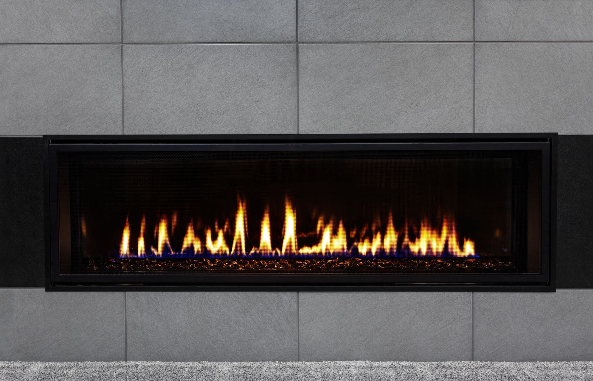 Modern wall-mounted gas fireplace with flames in a gray tiled surround