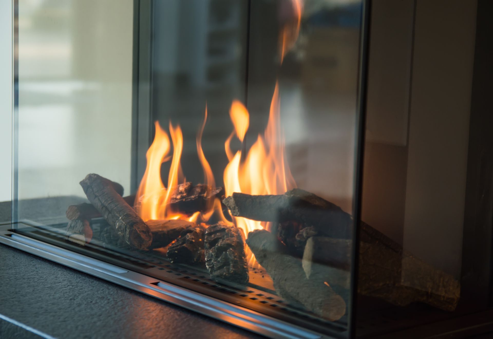 Modern fireplace with bright orange flames behind glass in a contemporary room