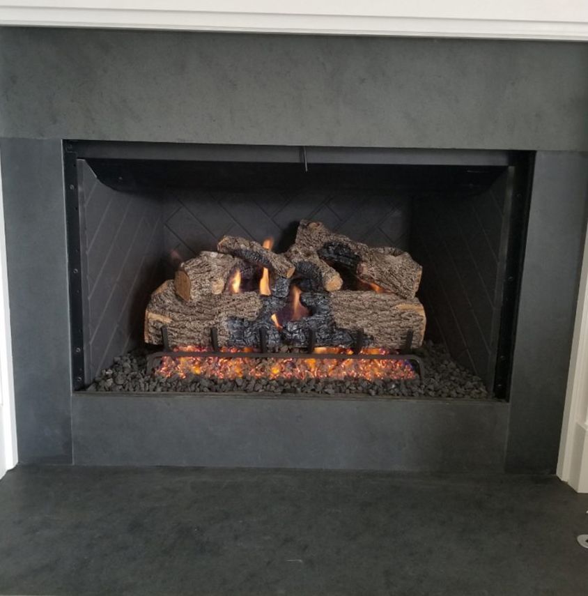 Modern fireplace with glowing embers and stacked logs in a black hearth opening