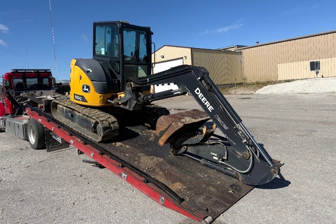 John Deere mini excavator on a trailer, ready for transport.