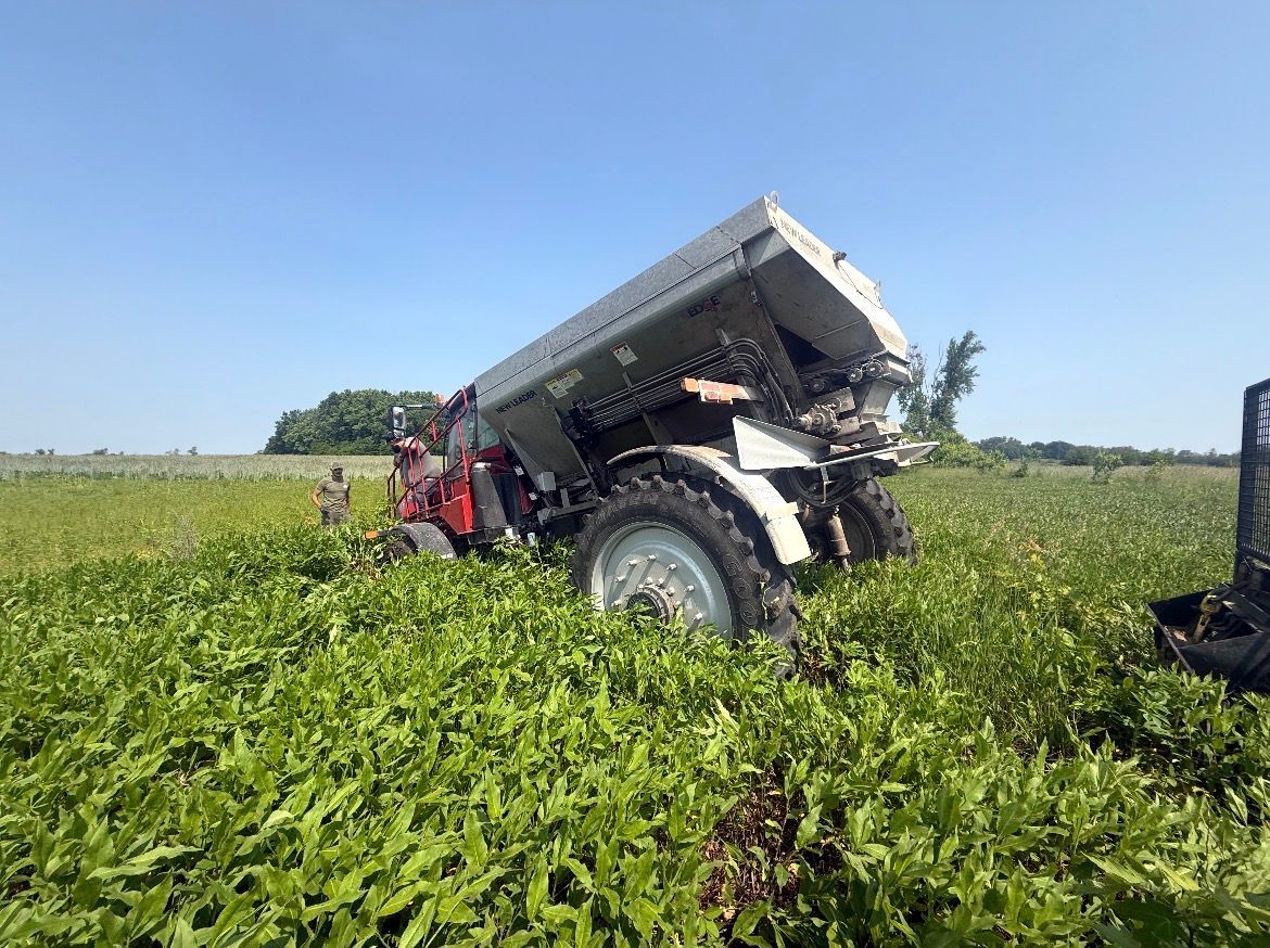 Tractor with a raised bed in a green field under a clear blue sky.
