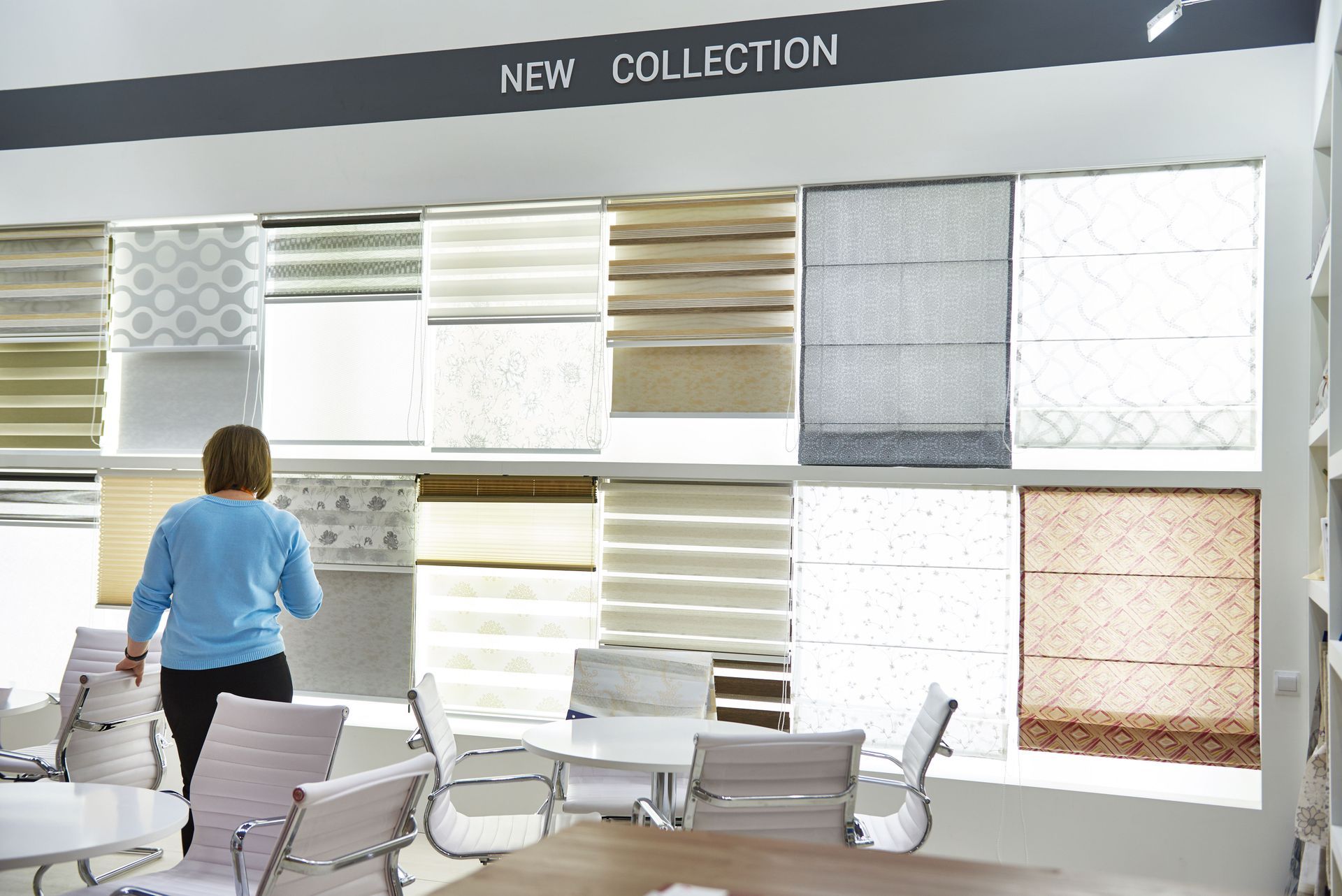 Woman looking at a display of window blinds in a showroom. 