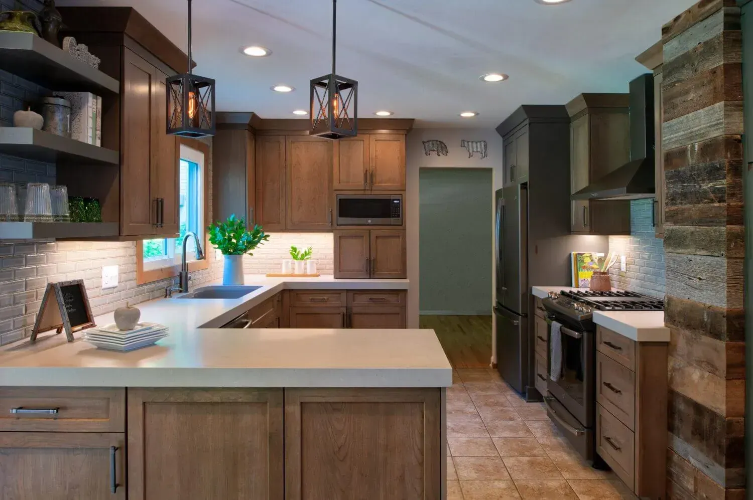 U-shaped kitchen with wood cabinets, white countertops, black appliances, and pendant lights.