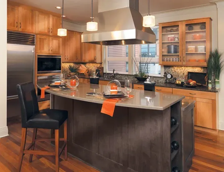 Modern kitchen with wood cabinets, island with seating, stainless steel appliances, and wood floor.