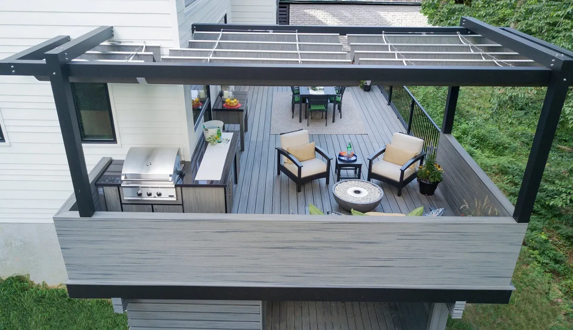 Wooden deck with outdoor kitchen, seating area, and overhead pergola.