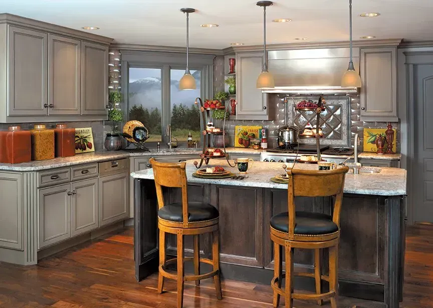 Kitchen with gray cabinets, granite countertops, and wooden island with two barstools.