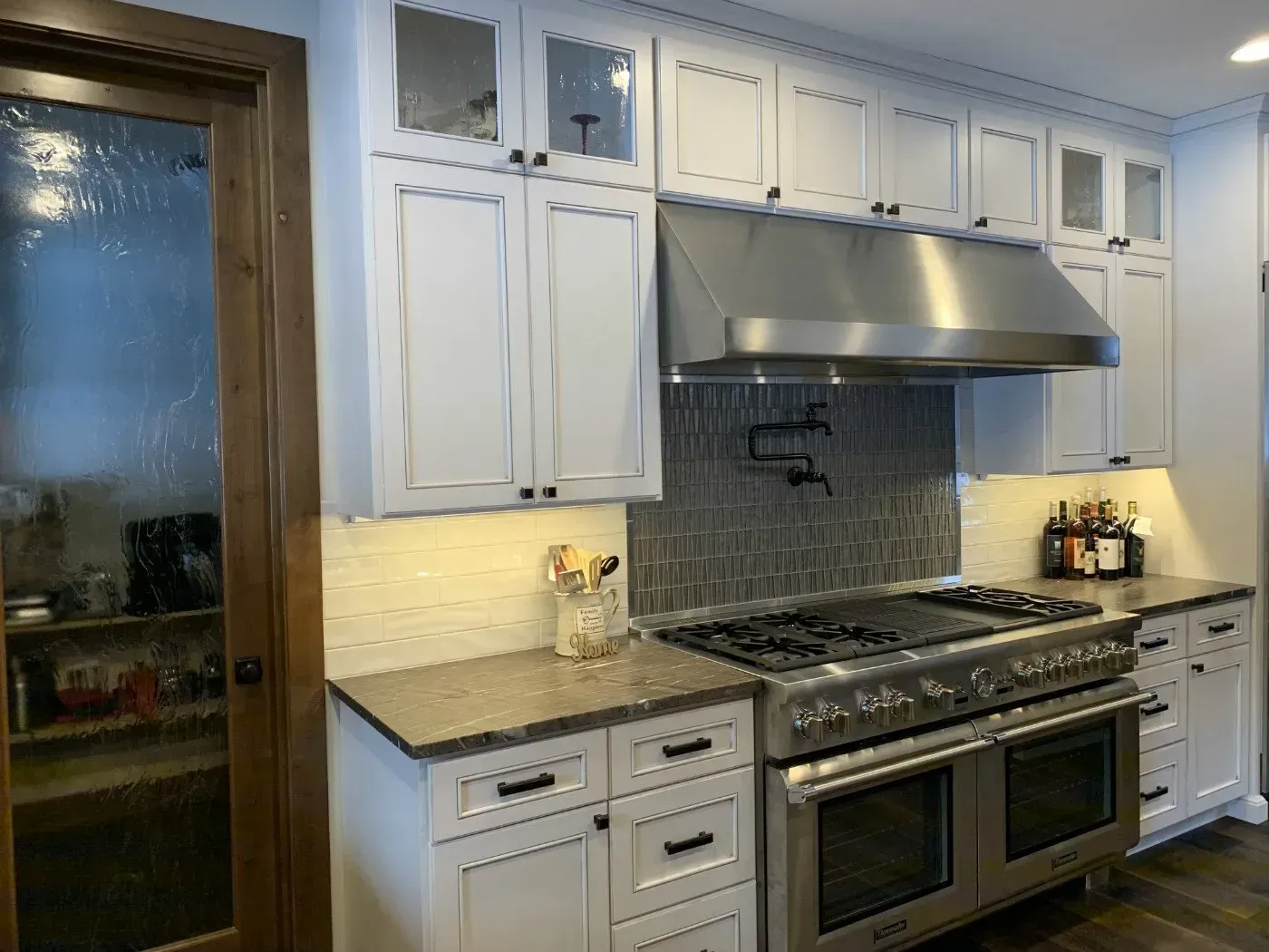 White kitchen cabinets with black hardware and stainless steel appliances.