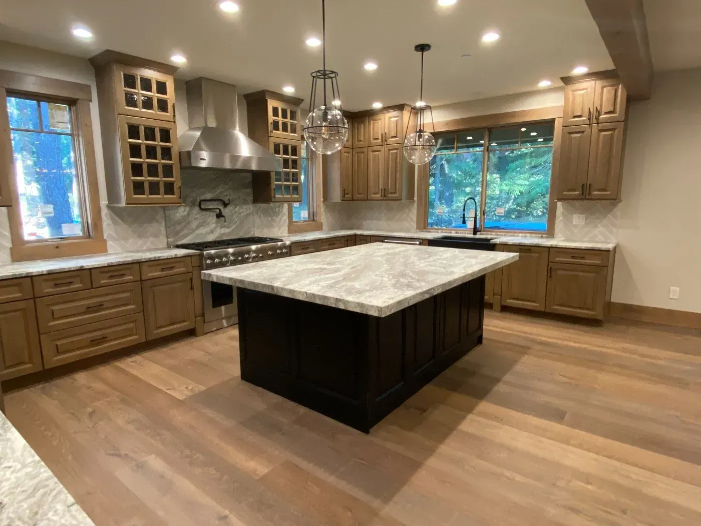 Spacious kitchen with wood cabinets, large island, granite countertops, and hardwood floors.