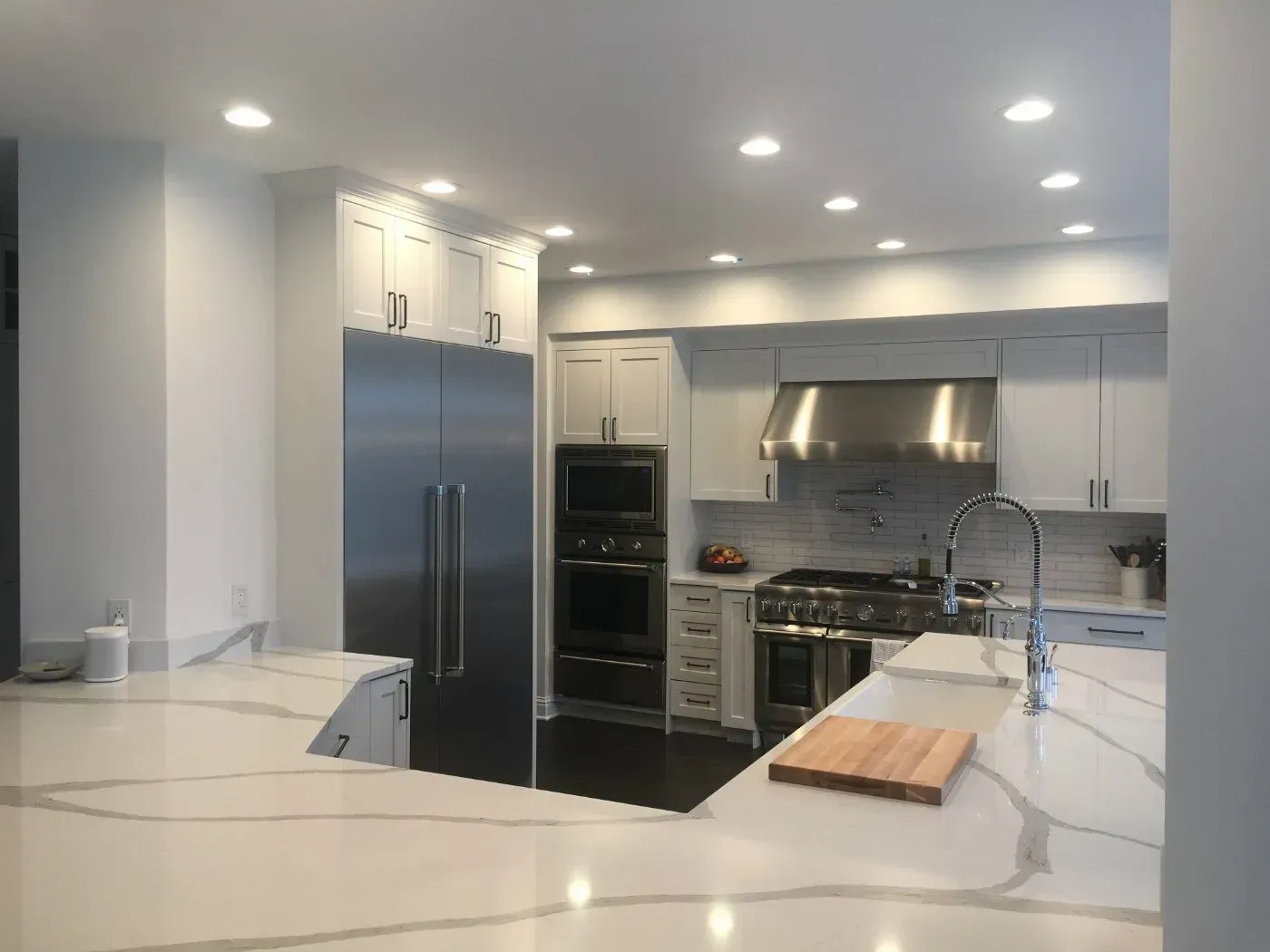 Modern kitchen with white cabinets, stainless steel appliances, and marble countertops.