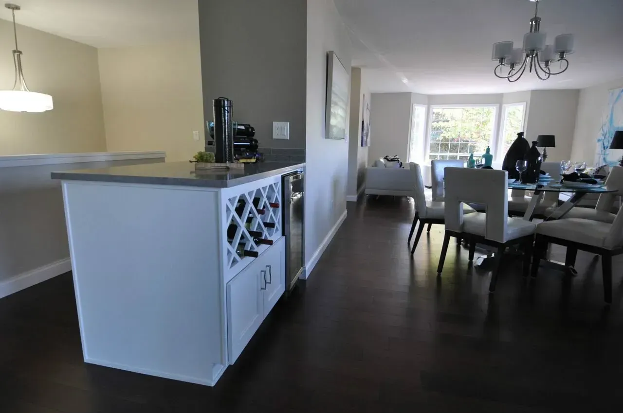 White wine bar cabinet with dark wood floors, open concept living area.