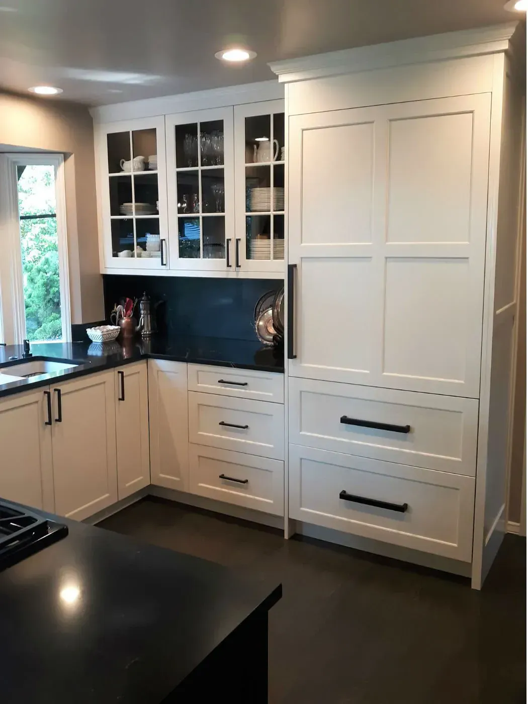 White kitchen cabinets with black countertops and hardware.