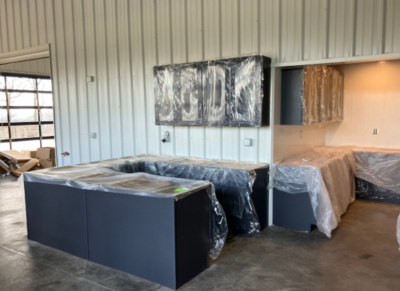 Unfinished kitchen with wrapped cabinets, island, and countertops in a large open room.
