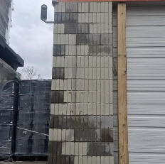 Partially built cinder block wall beside a gray metal roll-up door at a construction site