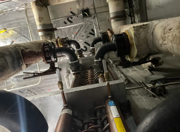 Industrial pipes and valves with insulation in a mechanical room, viewed from below