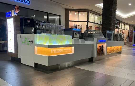Indoor mall kiosk with glowing blue and orange panels beside a tiled walkway