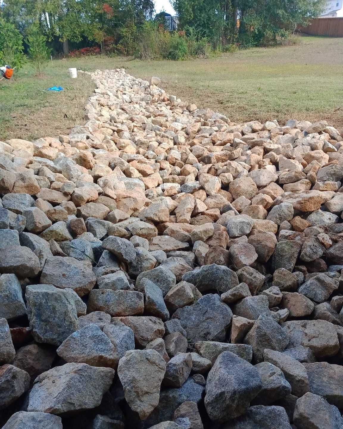 A pile of rocks in a field with trees in the background
