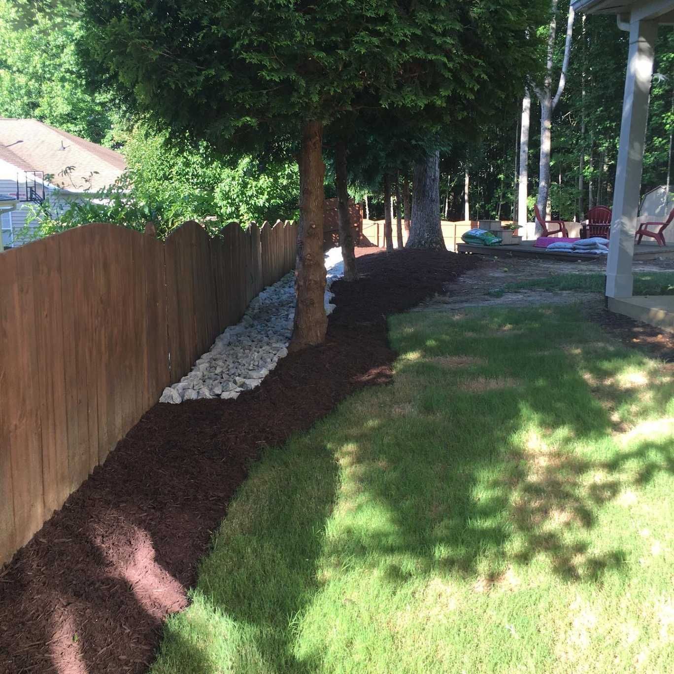 A wooden fence surrounds a lush green yard