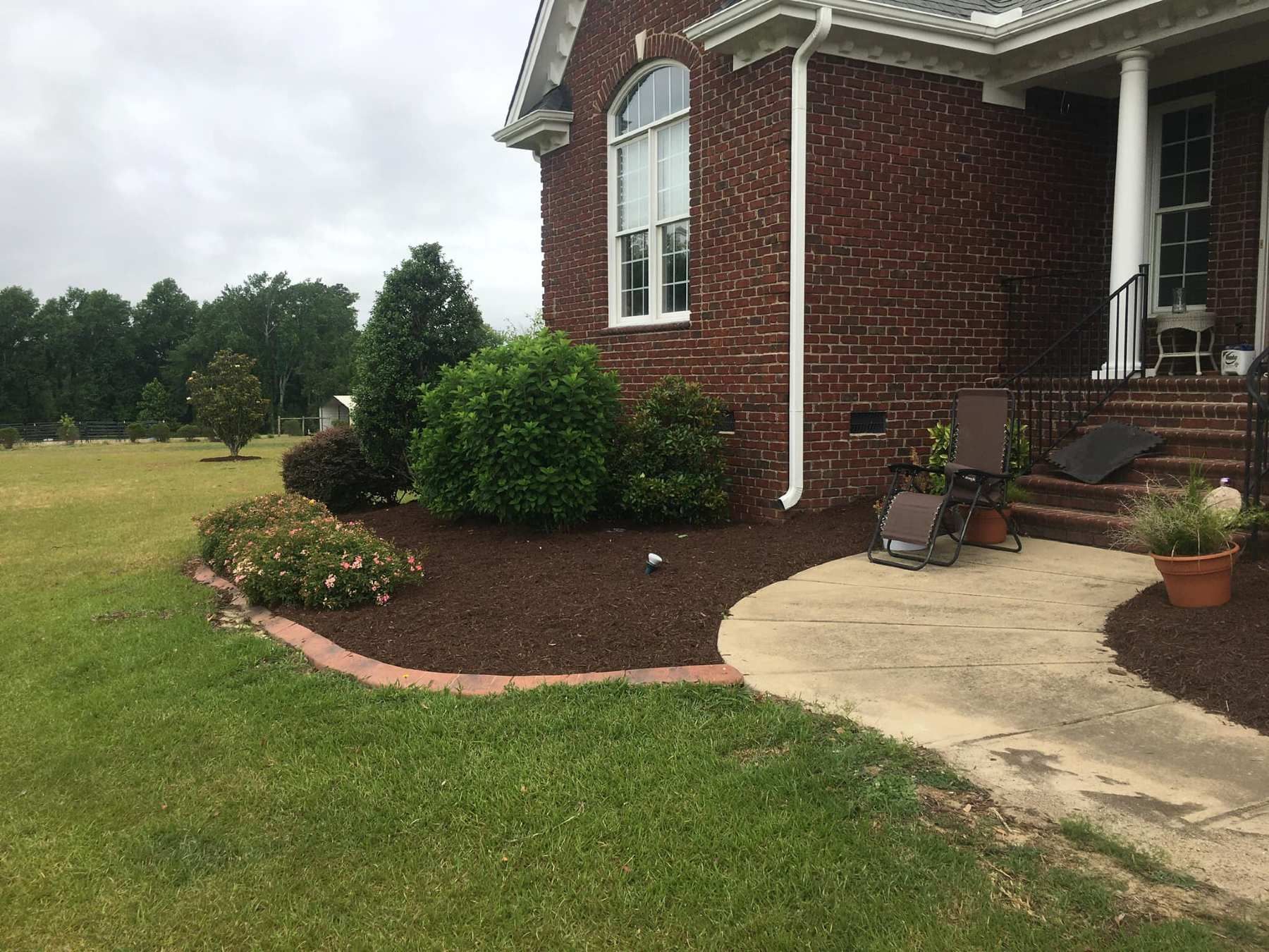 A brick house with a patio and a lawn in front of it.