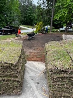 A stack of sod is sitting on top of a pile of dirt in a yard.