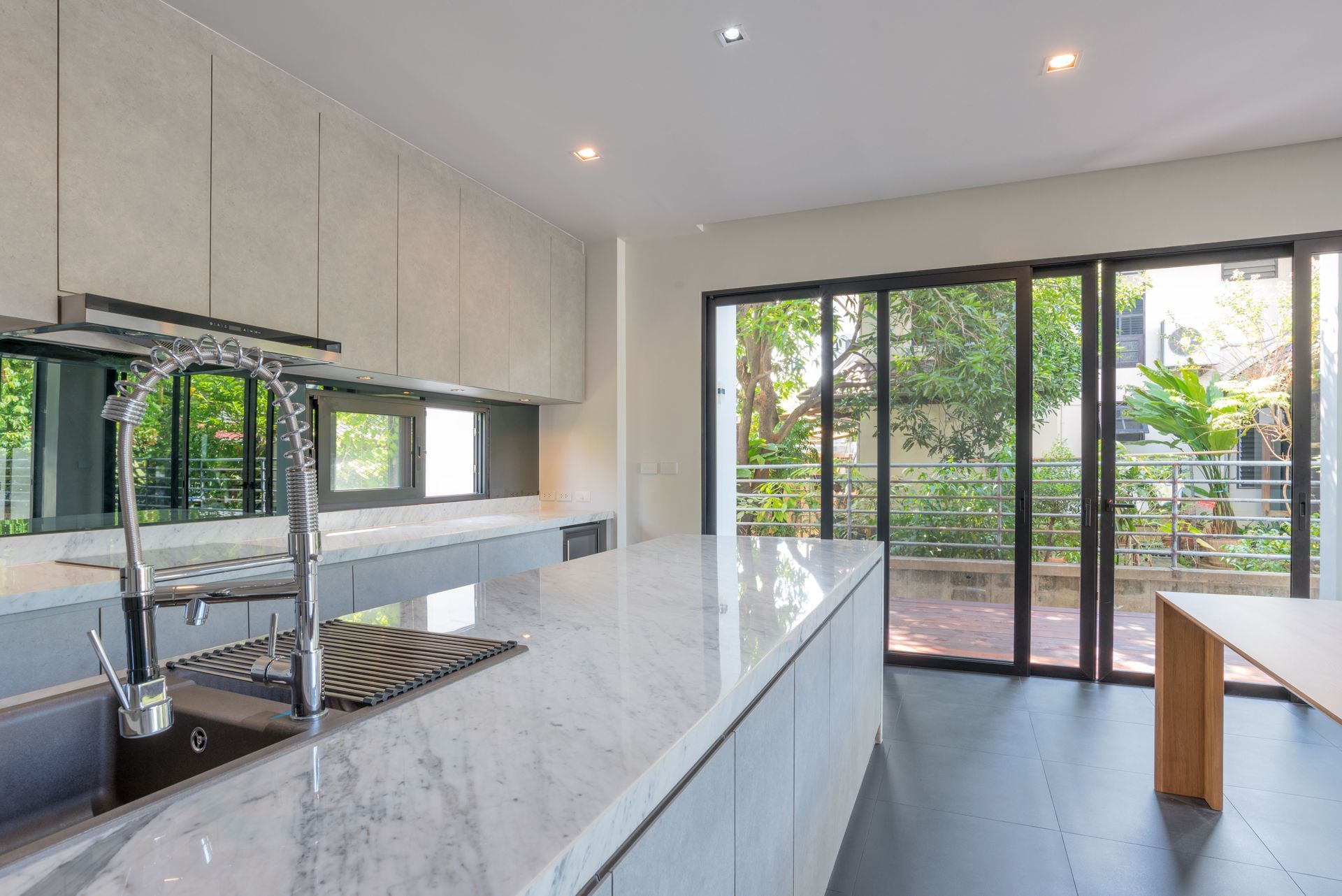 Modern kitchen with marble island, stainless steel faucet, and sliding glass doors to a patio.