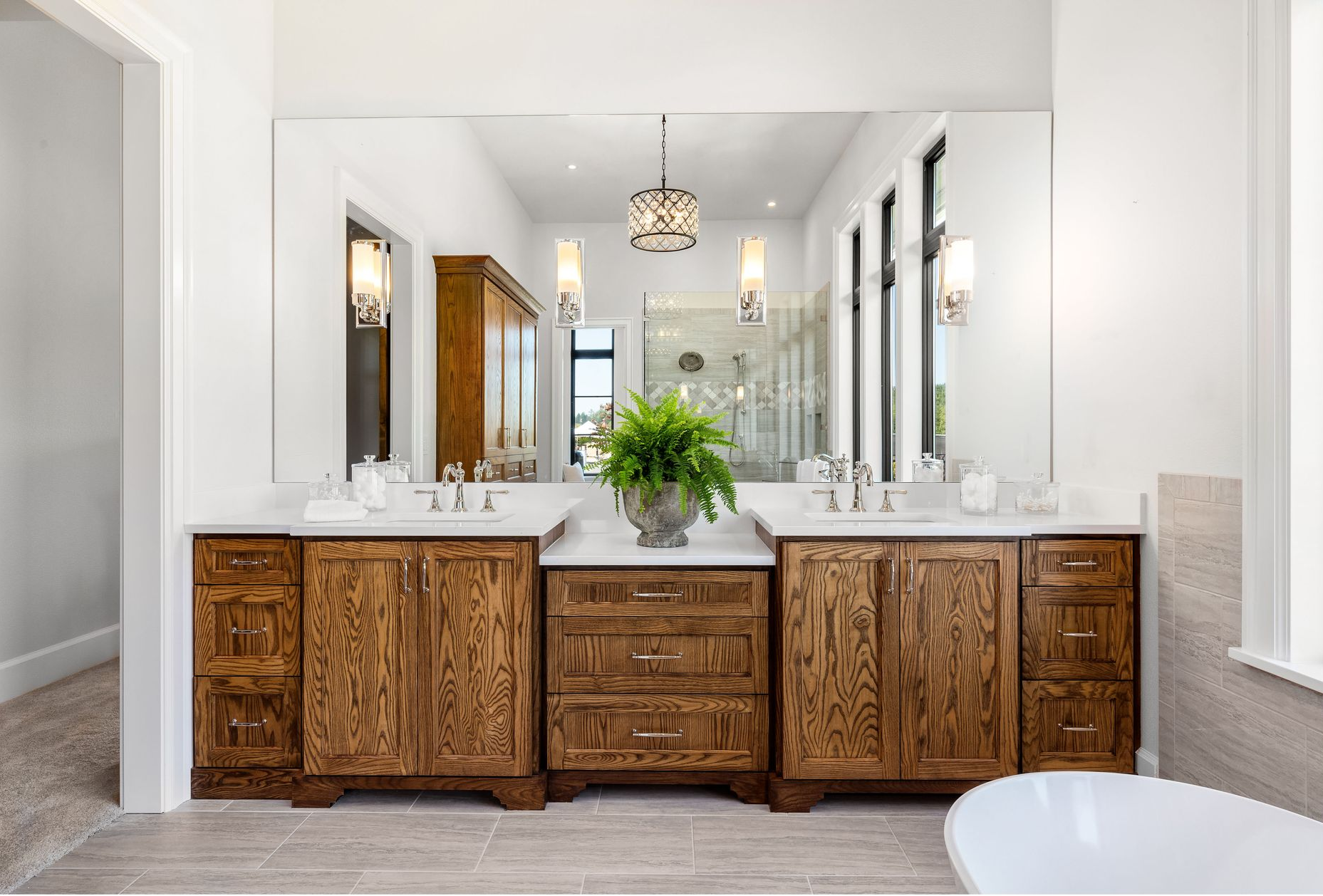 Double vanity bathroom with wood cabinets, large mirror, and decorative lighting.
