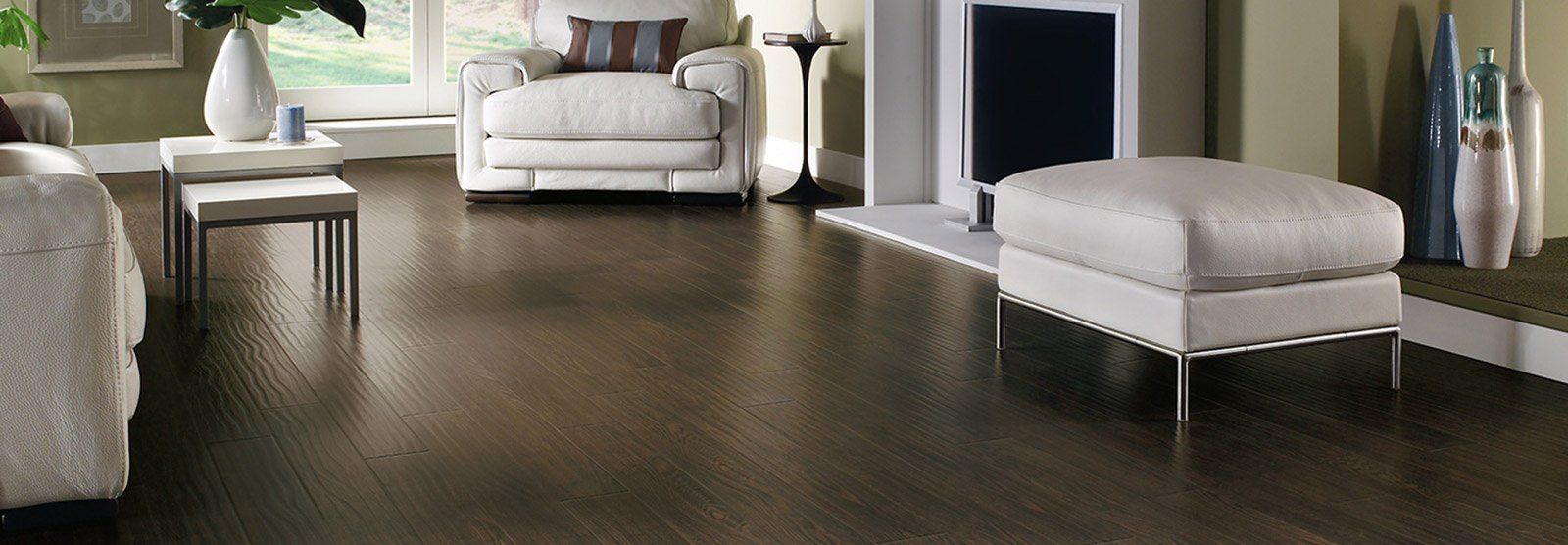 Living room with dark wood floor, white furniture, fireplace, and decorative vases.