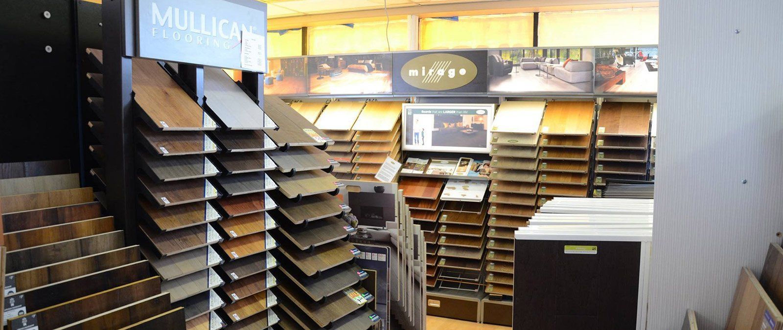 Interior of a flooring showroom displaying samples of wood flooring arranged on angled display racks.