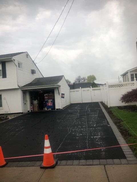 A driveway leading to a house with a garage and a white fence.