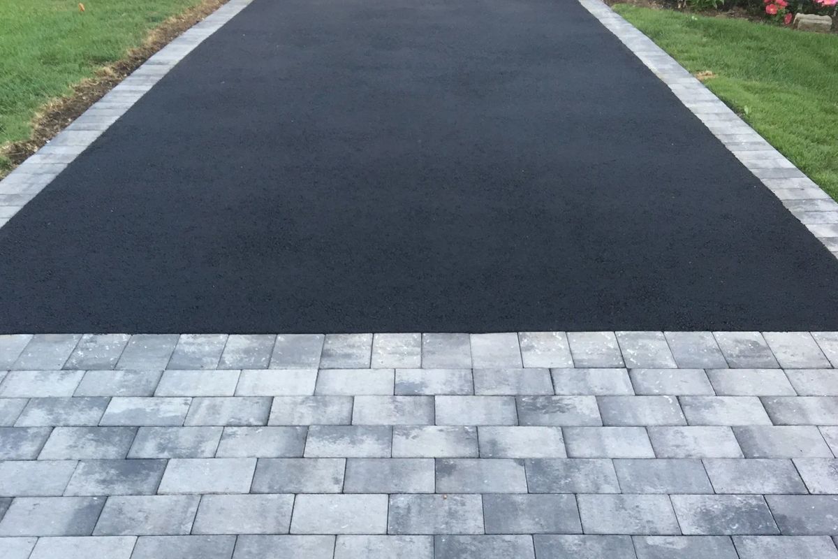 A black asphalt driveway with a brick border