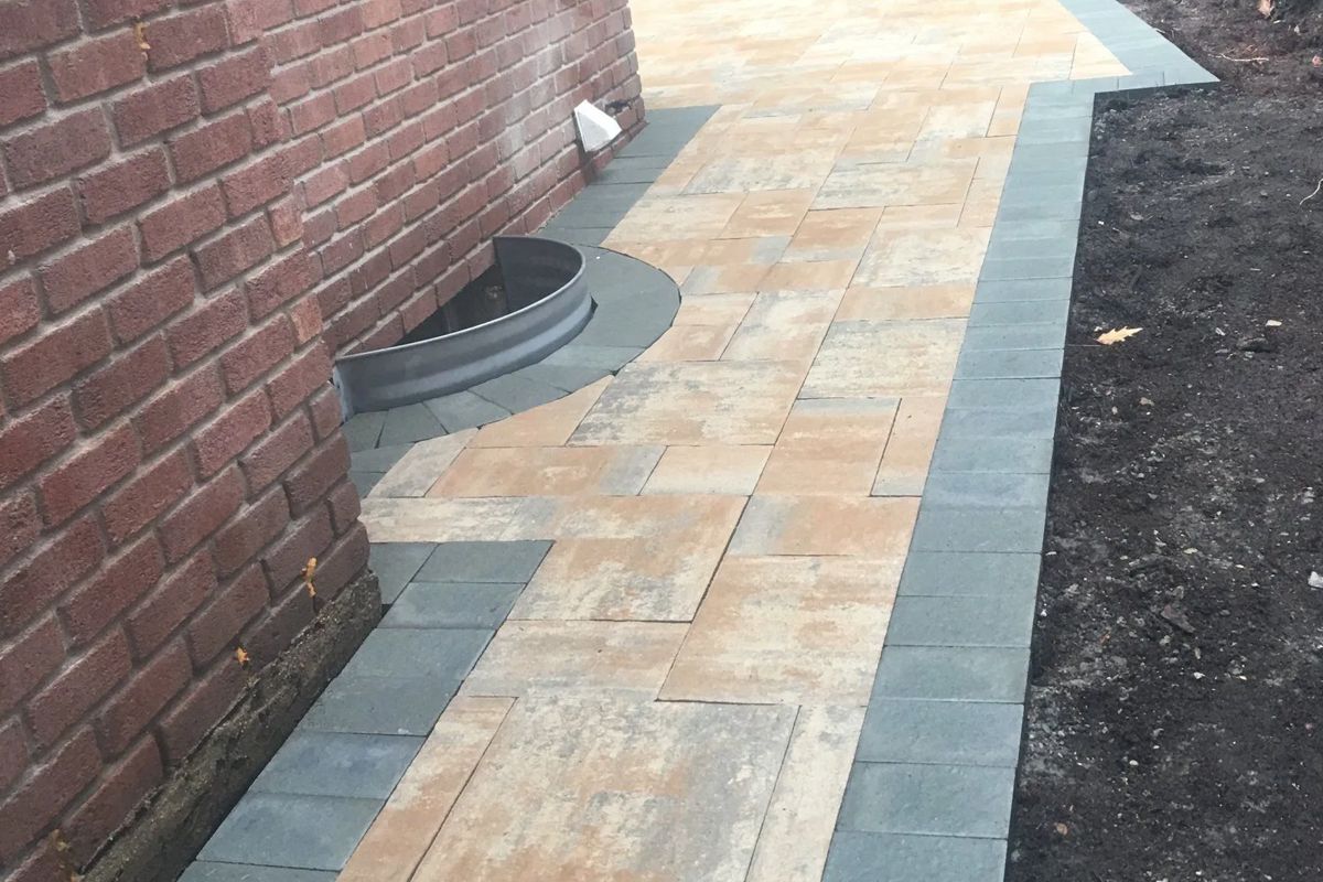 A sidewalk is being built next to a brick wall.